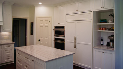 Full height wall of cabinets with built in double ovens and beverage station