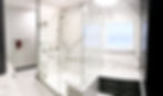 wide fisheye view of white porcelain wall shower with bench on the right side to site on