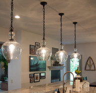 Bubble glass pendent lights above center island have matte black chains to dangle from
