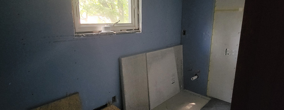 Light shines through full bath window on newly hung and painted drywall