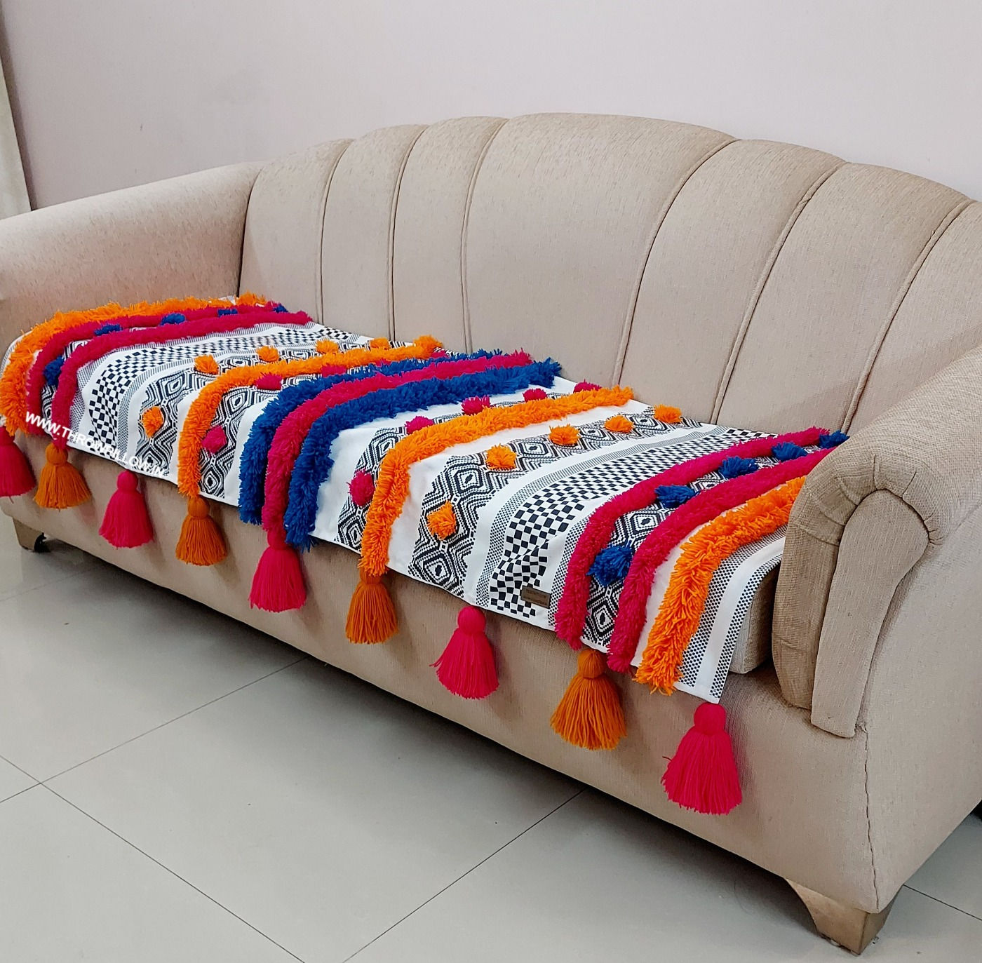 "Boho-inspired sofa cover with multicolored pattern and vibrant tassels"