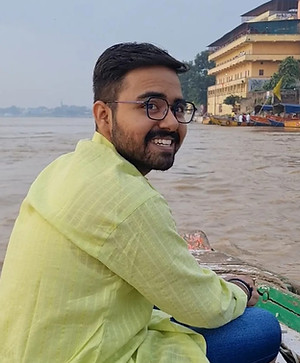 Titas Nandi's sitting on a boat in the river Ganges with one of the ghats in the background