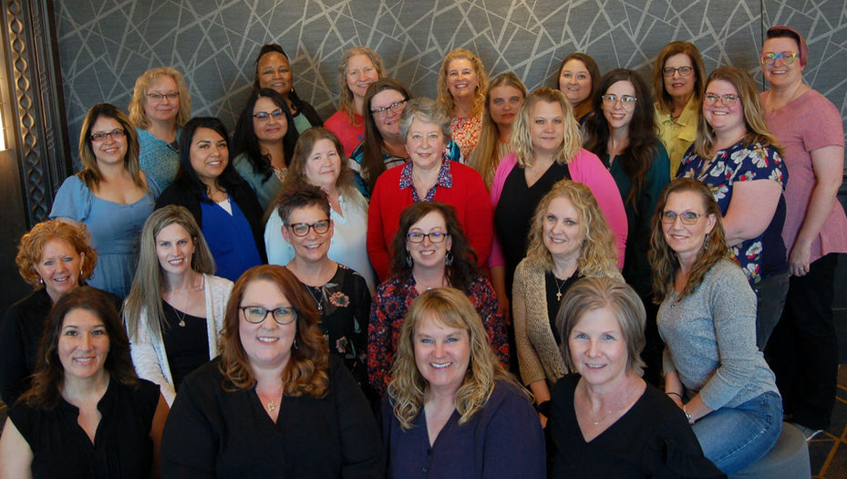 Group photo of smiling women posing together with variety of attire.