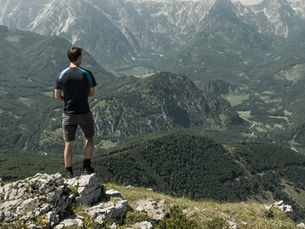 Homem olhando o horizonte no topo de uma montanha.