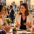 Executivos discutem projetos em uma reunião ao ar livre ao pôr do sol, com a cidade ao fundo.