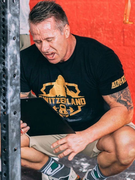 Mann im schwarzen T-Shirt liest Klemmbrett beim Training