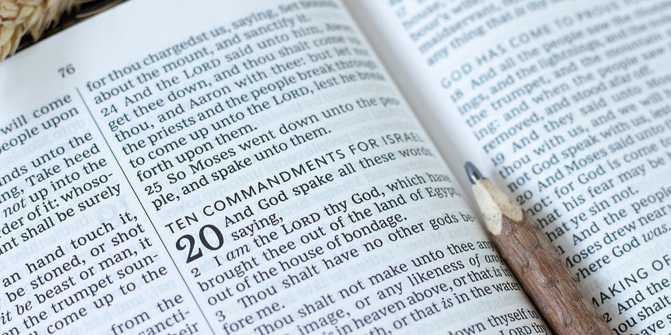 Open Bible with visible Ten Commandments text and a pencil resting on the page, in a quiet reading scene.