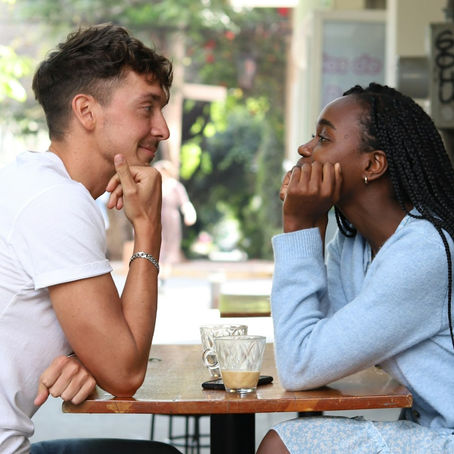 Interracial couple on a date seated at a table and staring into each others eyes