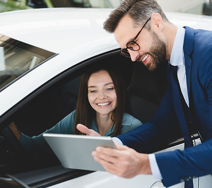 Male handsome caucasian shop assistant showing explaining to a female client customer car