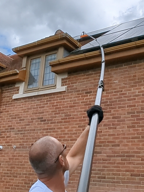 A Shining Windows Operative Cleaning solar panels from the ground