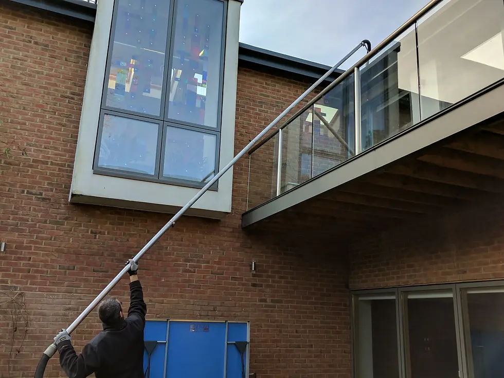 Commercial Gutter Clearance service being completed using a gutter vacuum to reach above and beyond a balcony.