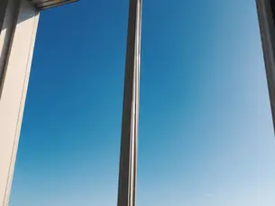 Eye-level view of a clear blue sky reflecting on a clean window