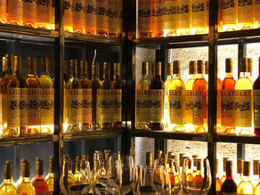 Backlit wine and aperitif bottle display in a restaurant dining room