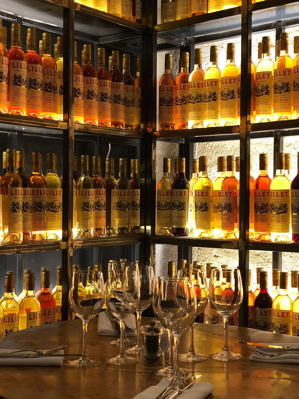 Backlit wine and aperitif bottle display in a restaurant dining room