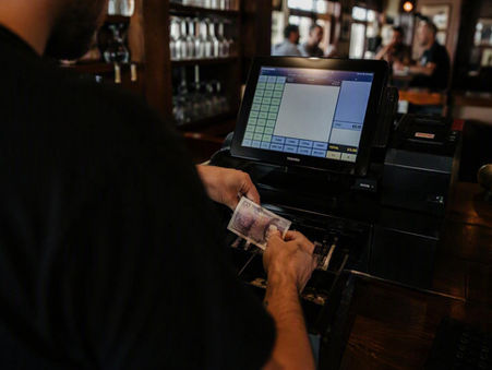 A bar team member taking money from a till
