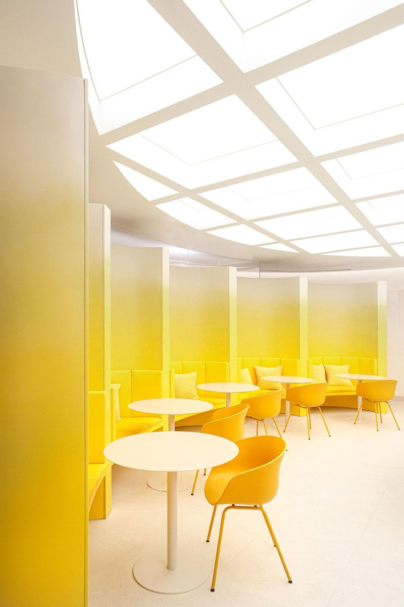 All White Ceiling with Platform Lighting and Bright Yellow Interior for an Office Cafeteria