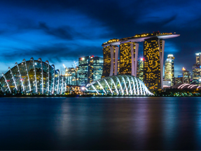 Singapore skyline at night with Marina Bay Sands and domed gardens lit up. Blue sky, city lights reflecting on the water create a vibrant mood.