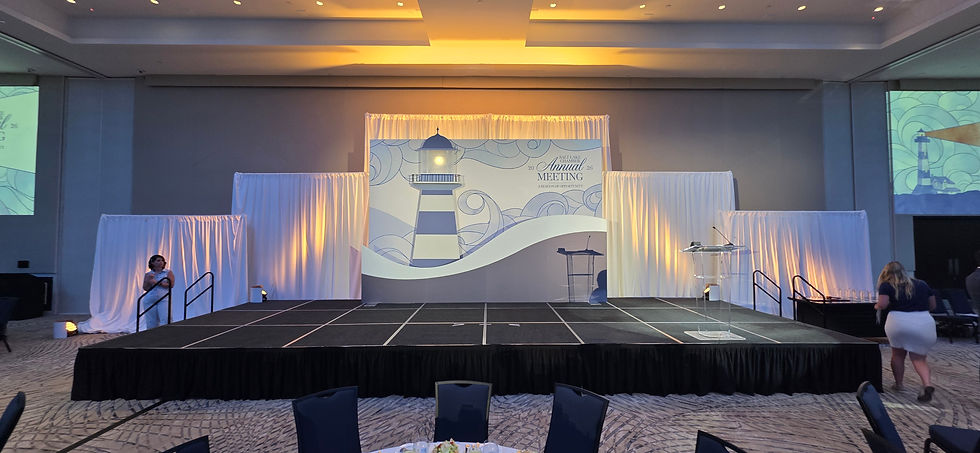 Executive stage setup with modular panels, white draping, custom lighthouse backdrop, and stage lighting provided by Aspen Peak Productions for an event in Utah.