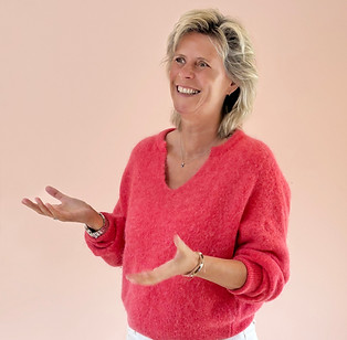 Een vrolijke vrouw in een warm rode gekleurde trui lacht vrolijk en belichaamt een gevoel van warmte