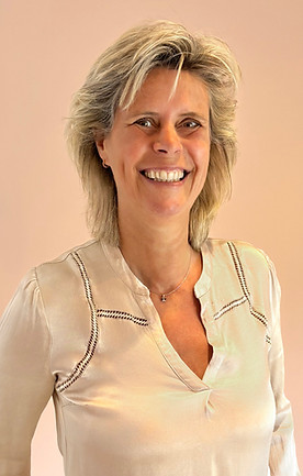  vrouw met blond haar in een goudkleurige blouse, lachend en vastgelegd in een moment van kalmte en zekerheid