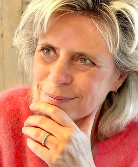 Een vrouw in een warm rode trui, die comfort en vreugde uitstraalt in haar uitdrukking