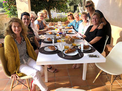 Een groep vrouwen rond een tafel, genietend van een gedeelde maaltijd, omringd door een glimlach en 