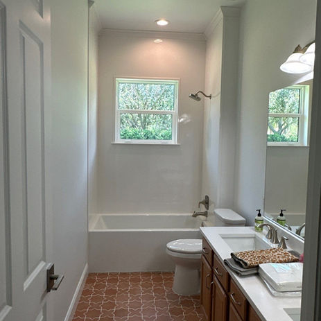 Full bathroom with tub, toilet, double vanity, and tiled floor.