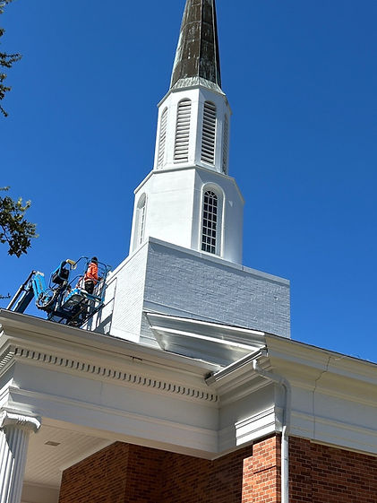 Worker in blue lift on white church steeple