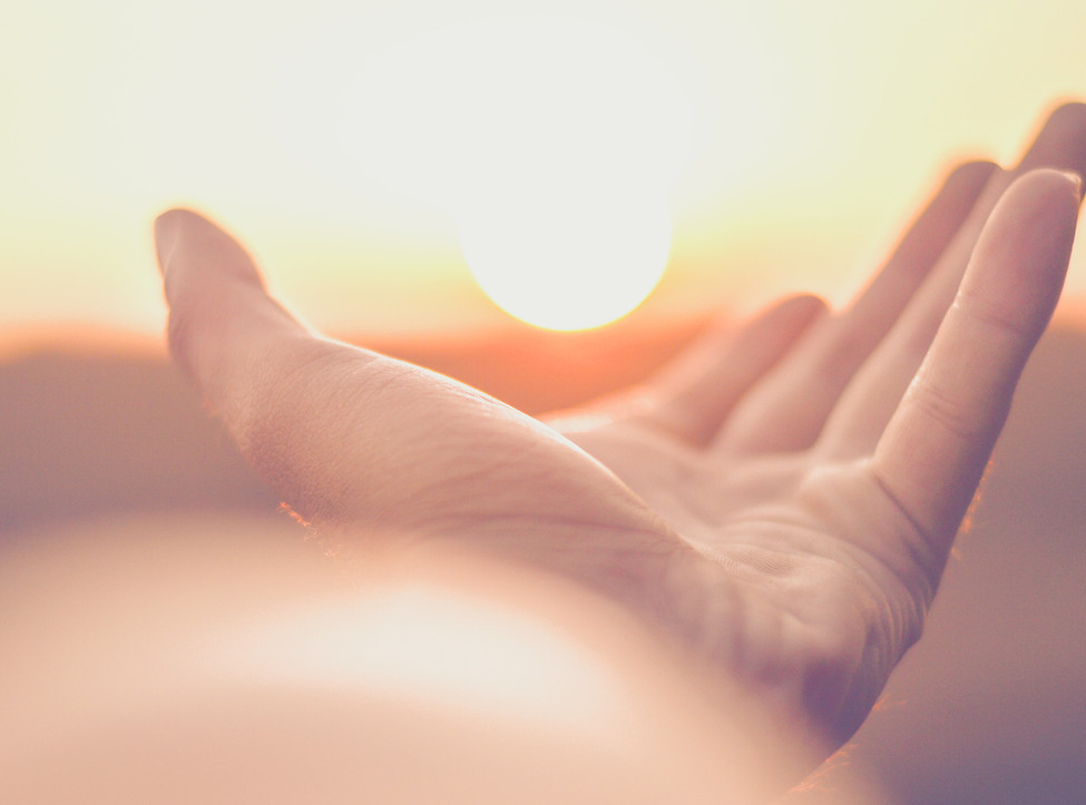 persons left hand on white with sunset in background