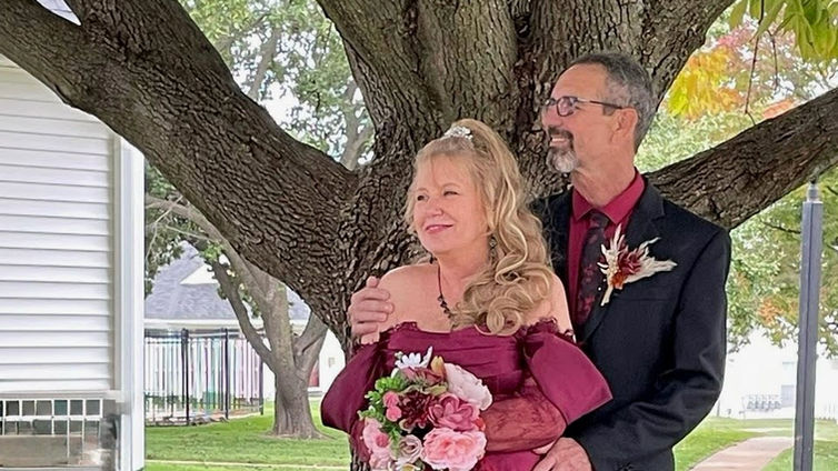 Couple standing under tree for outdoor wedding portrait