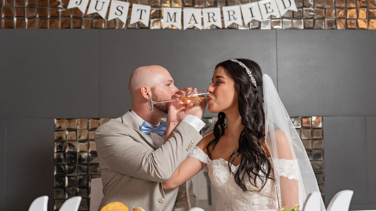Newlyweds sharing kiss at wedding reception table