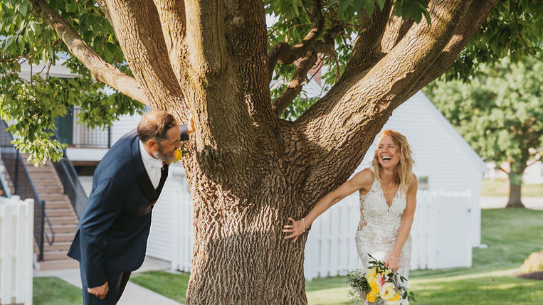 Couple standing under tree for outdoor wedding portrait