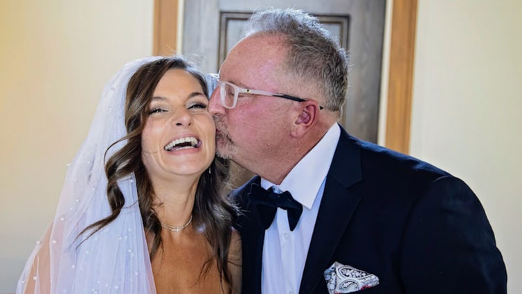 Newlyweds sharing kiss at wedding reception table