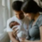 a woman and man smiling at a baby