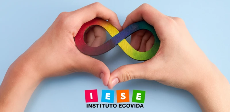 Símbolo da Neurodiversidade entre duas mãos em formato de coração representando a capado Curso Desvendando a Neurodiversidade do IESE Instituto Ecovida