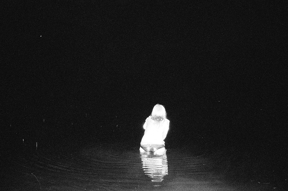 “a black and white photo of a woman standing in the sea from Lina Scheynius photo-essay for Tabayer jewelry
