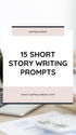 Text on a white background reads "15 Short Story Writing Prompts" with a website link below. A laptop and desk items are partially visible.