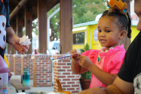 little girl painting a pumpkin