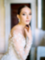 Bride in white dress, adorned with earrings, hand gracefully touching a toss
