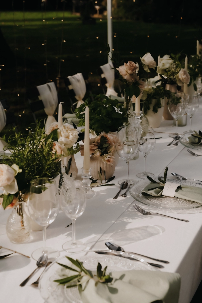 Einzigartige Hochzeitspapeterie und Hochzeitsdeko für die freie Trauung und Gartenparty im mediterranen Flair in Deutschland mit handgeschöpftem Papier und persönlichen Namenskärtchen. Man sieht einen Lichterketten Himmel mit weißen und beigenen Rosen