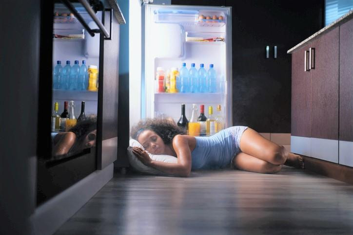 Woman sleeping on the floor with the fridge open