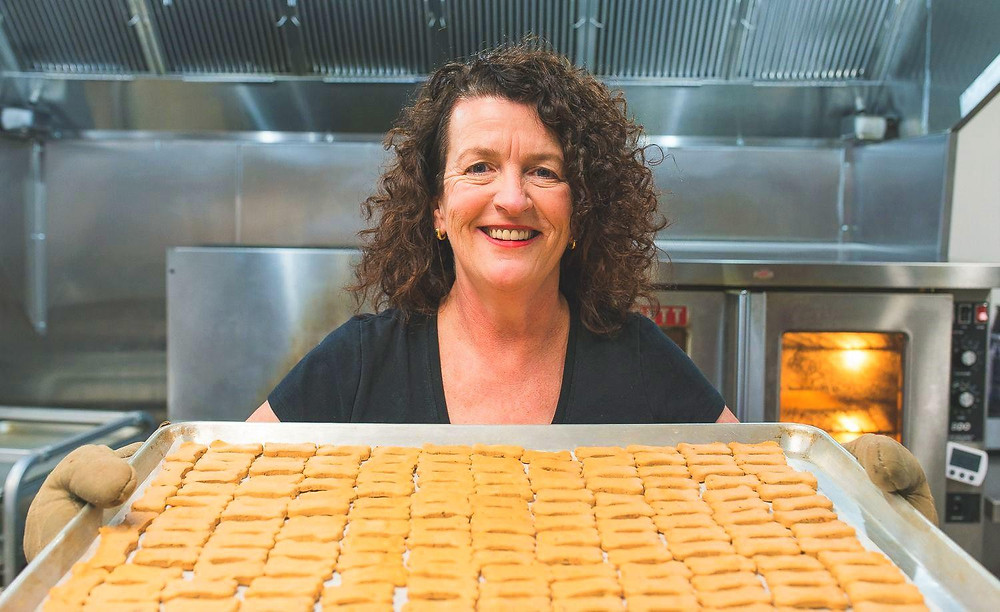 Kate is standing in front of the oven with a tray of dog biscuits