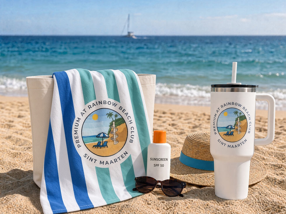 Beach towel, sunscreen, sunglasses, sun hat, and reusable tumbler on a sandy beach in Sint Maarten with turquoise Caribbean waters in the background.
