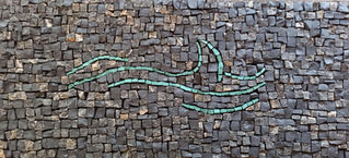 Mosaïque murale rectangulaire composée de cubes de pierre brute dans des tons gris foncé et anthracite, ornée d'un motif abstrait - en forme de vague - fluide formé par des lignes sinueuses en tesselles de couleur vert d'eau ou turquoise claire.