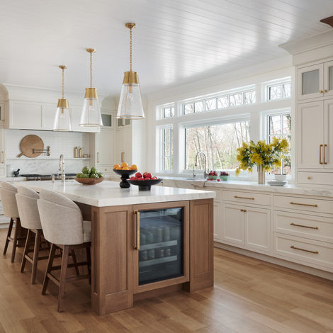 New traditional Wellesley MA kitchen with white cabinetry, marble counters, white oak island, and brass pendants.