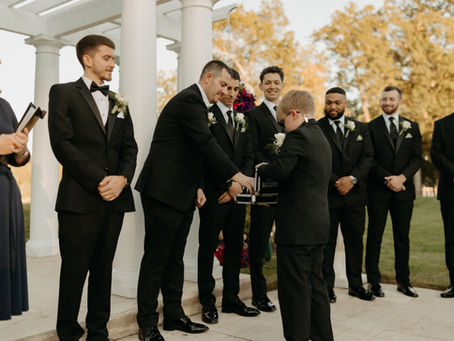 A young ring bearer hands off the rings to the best mean after the wedding ceremony procession