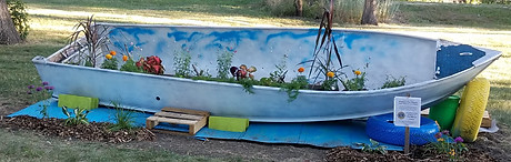 Picture of a painted boat filled with flowers in a garden area
