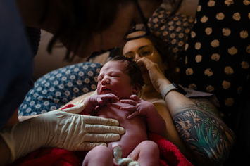 hebamme-mit-neugeborenem-nabelschnur-geburtsfotografie