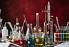 red background assortment of laboratory glassware beakers flasks tubes.jpg