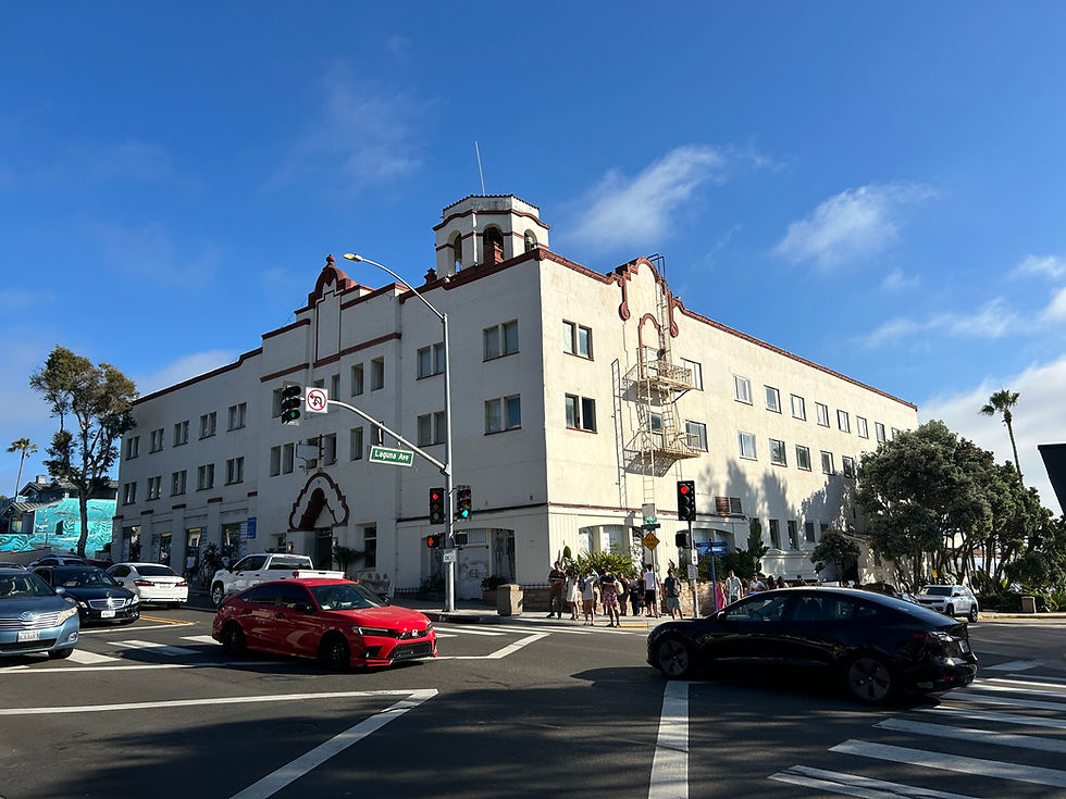 The Hotel Laguna in Laguna Beach, CA, as seen across Pacific Coast Highway, with busy cars and pedestrians.